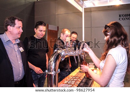 MOSCOW-APRIL 27: Girl pouring beer to glass from beer tap at the international exhibition of market production beer, and low alcohol drinks Brewer on April 27, 2011 in Moscow