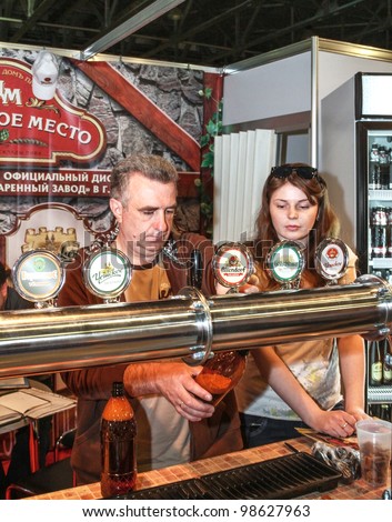 MOSCOW-APRIL 27: Man pouring beer to glass from beer tap at the international exhibition of market production beer, and low alcohol drinks Brewer on April 27, 2011 in Moscow