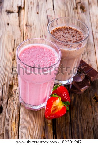 Fresh milk, strawberry and chocolate drinks on wodeen table, assorted protein cocktails with fresh fruits.