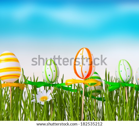 Beautiful meadow and easter eggs with blue sky. Easter concept. Fresh green grass. Color easter eggs.
