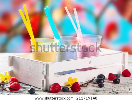 Fresh milk, raspberry, blueberry and vanilla drinks on wooden table, assorted protein cocktails with fresh fruits and nature background. Healthy lifestyle.