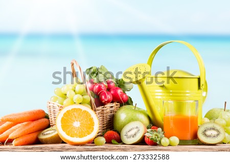 Garden concept, fresh fruits, carrot juice and vegetables on wooden table, watering can, seeds, plants