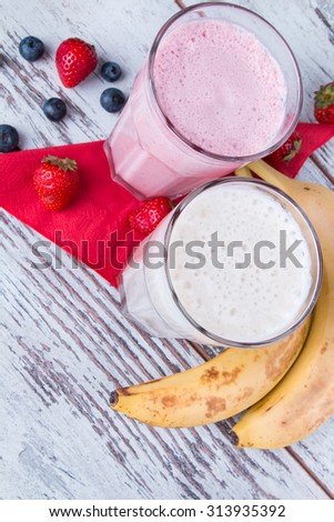 Fresh milk, strawberry and banana drinks on wooden table, assorted protein cocktails with fresh fruits.