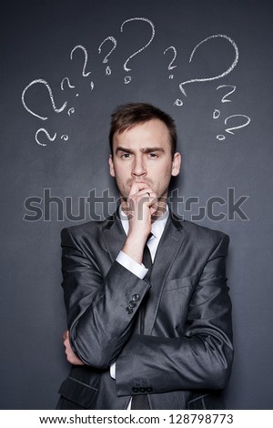young handsome confused businessman with chalk drawn question marks