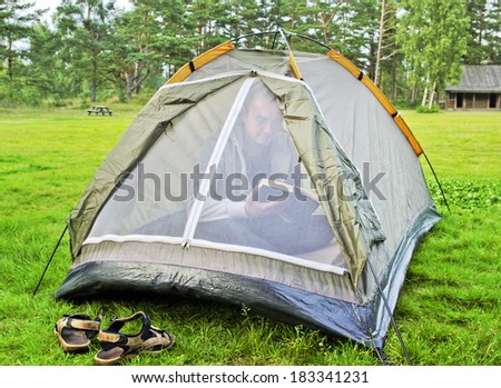 Young man is reading a book inside the tent.