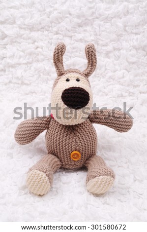 Beige crocheted bear sitting on the white cloth
