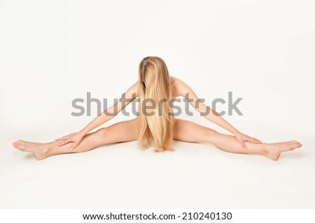 Artistic nude of an attractive slim female gymnast with very long blond hair working out in front of bright background