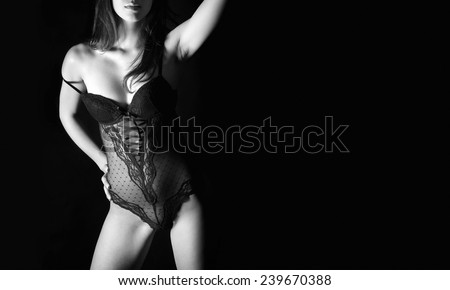 Closeup of perfect female body in black lingerie, studio shot in front of black background, monochrome photo with copy space on the right side of the image