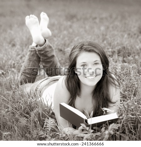 Portrait of a beautiful young woman reading a book, monochrome outdoor photo taken in summer