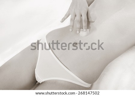 Monochrome closeup of a young woman with an ice cube on her wet belly
