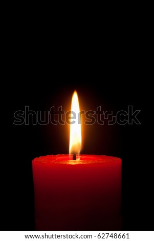 A single burning red candle isolated in front of black background