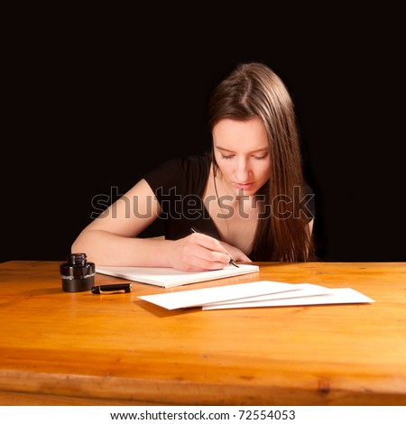 Pretty young woman writing a letter at an old table