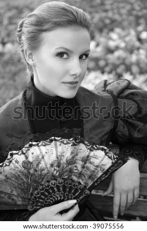 Pretty woman with a fan in a vintage dress