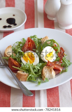 Soft-boiled egg, chorizo and rocket salad on a plate