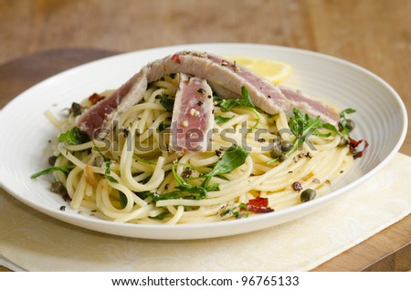Spaghetti with tuna steak, rocket and herbs on a plate