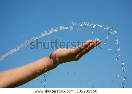 Water and hand against blue sky.