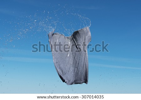 Wet gray shirt flying in blue sky.