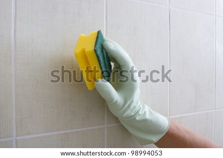 Hand cleaning tiled wall.