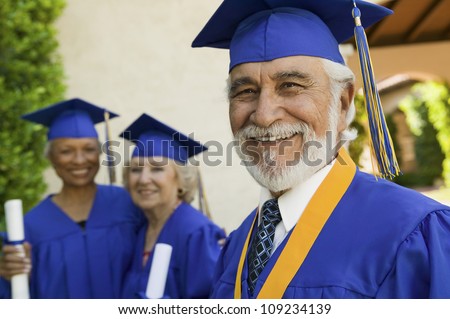 Portrait of a happy senior male graduate with female friends in background