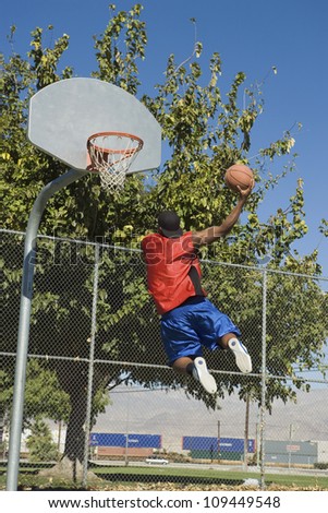 Rear view of African American man jumping to score basket