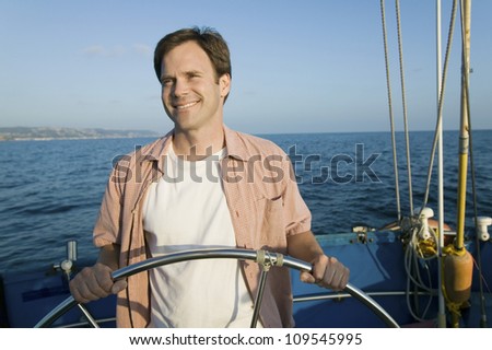 Happy mature man holding steering wheel of the yacht