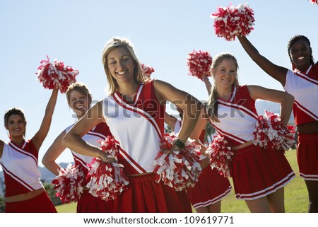 Portrait of cheerleaders with pom-pom on field