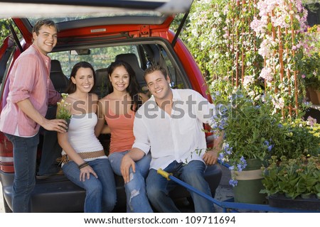 Group portrait of happy friends sitting in car at botanical garden