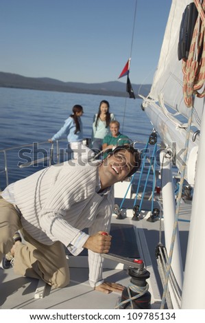 Man on a  sailboat with friends in the background