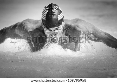 Black and white image of a competitive male participant swimming in a butterfly stroke