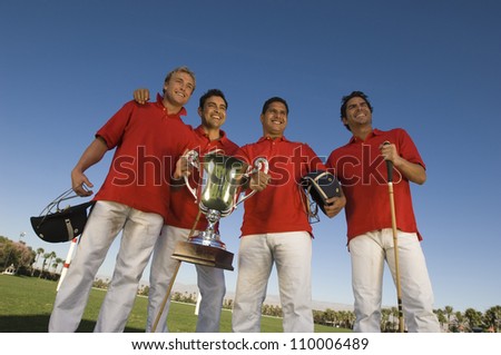 Low angle view of male polo players with trophy on field