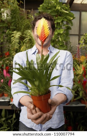 Man holding potted plant in front of face