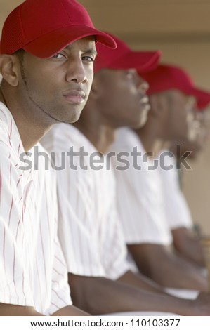 Portrait of a confident baseball player sitting with team mates in the background