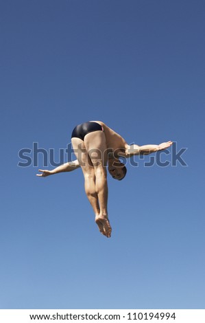 Diver diving in midair against clear sky