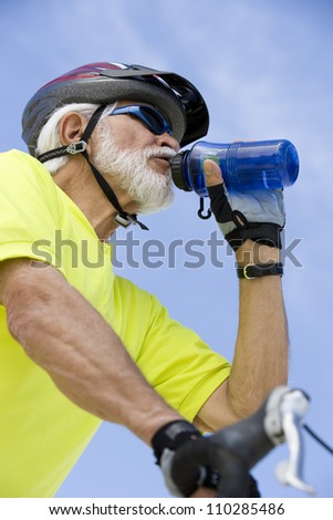 Senior male cyclist drinking water