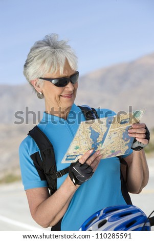 Senior female cyclist reading map