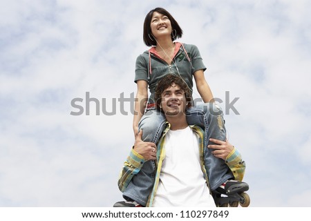 Young man carrying woman on shoulders from below