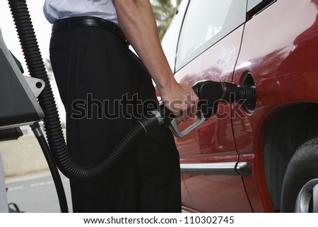 Lower body of a man refueling a car