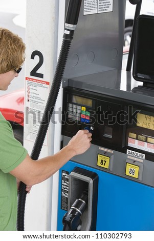 Young man using his debit card to pay for gasoline