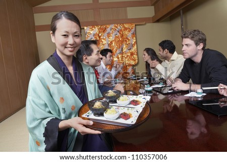 Waiter holding plates to serve food to people at restaurant