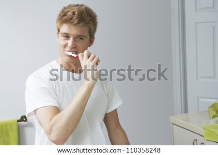 Young man brushing his teeth in bathroom