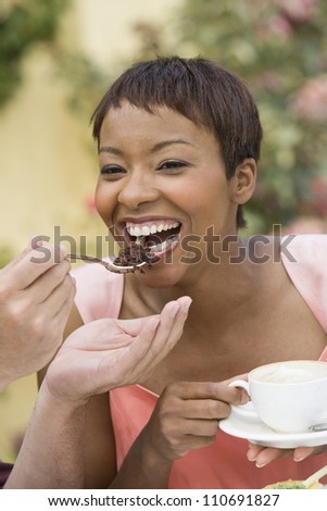 Man\'s hands feeding cheerful African American woman