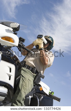Middle aged traffic officer looking through radar gun from below
