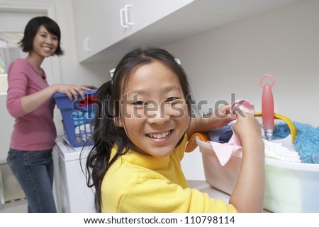 Portrait of a teenage girl helping her mother to wash clothes