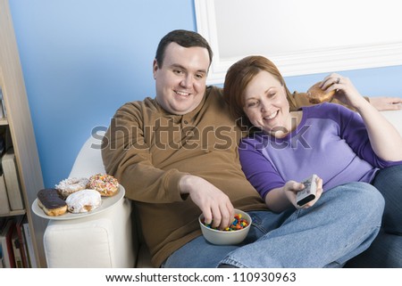 Obese couple watching television at home