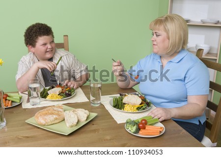 Obese mother and son having meal together at home