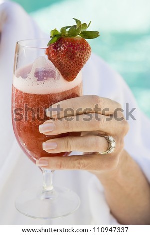 Close-up of senior woman\'s hand holding glass of strawberry shake