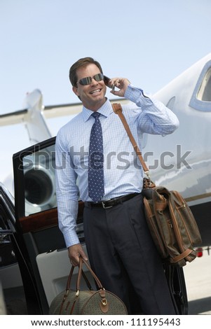 Businessman using cell phone with airplane in the background
