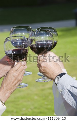 Four hands toasting wine glasses