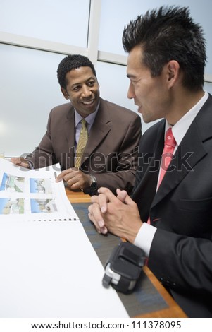 Happy African American businessman showing property samples to his business partner