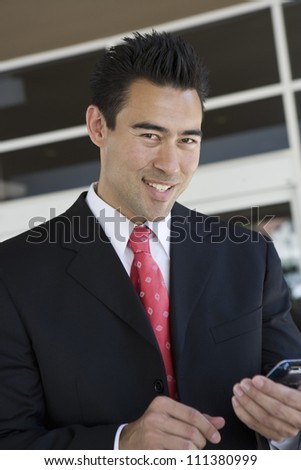 Portrait of happy Asian businessman holding mobile phone